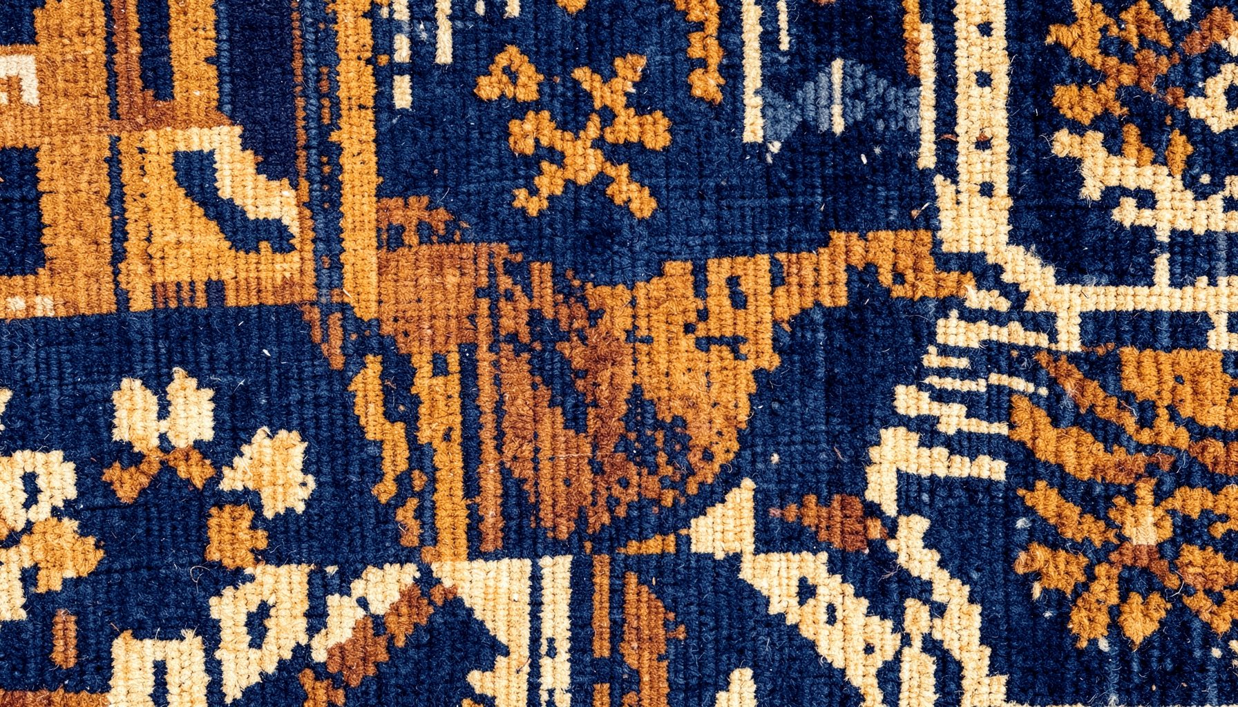Warm-toned abstract textile pattern in deep indigo, ochre, and cream, evoking Northern Nigerian woven fabric