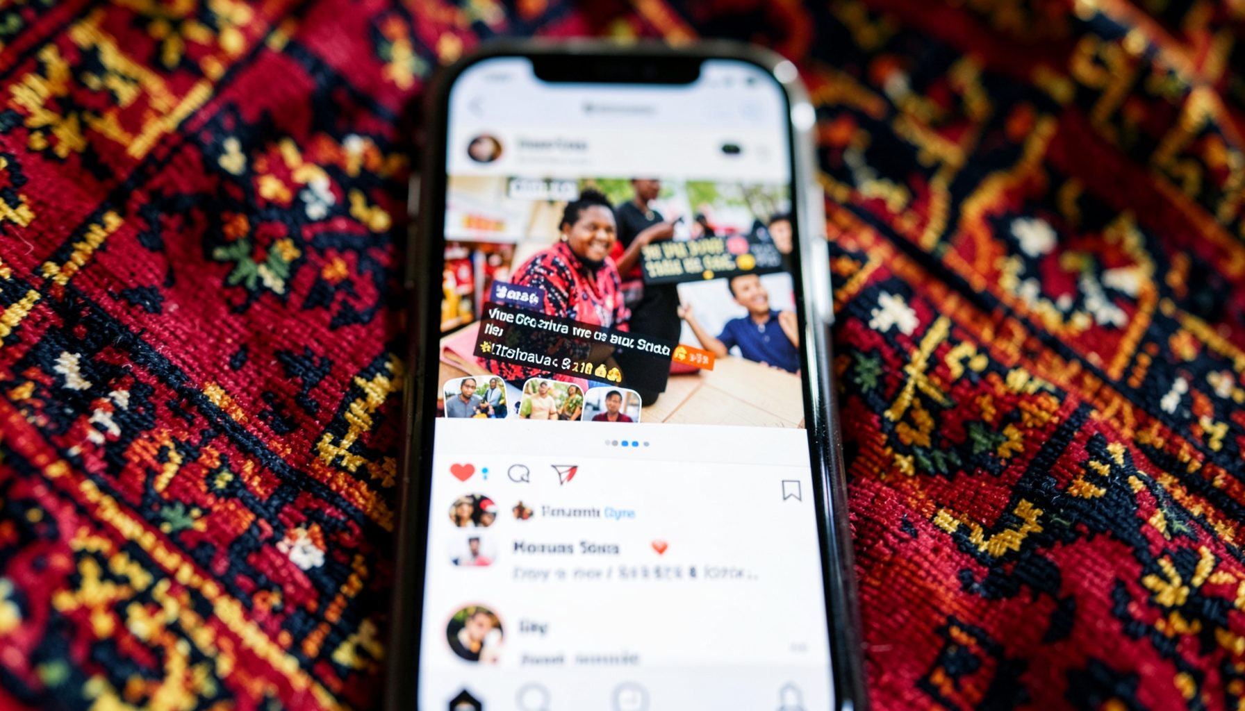 A close-up of a smartphone screen displaying a vibrant Instagram feed with Hausa text overlays, set against richly patterned fabric